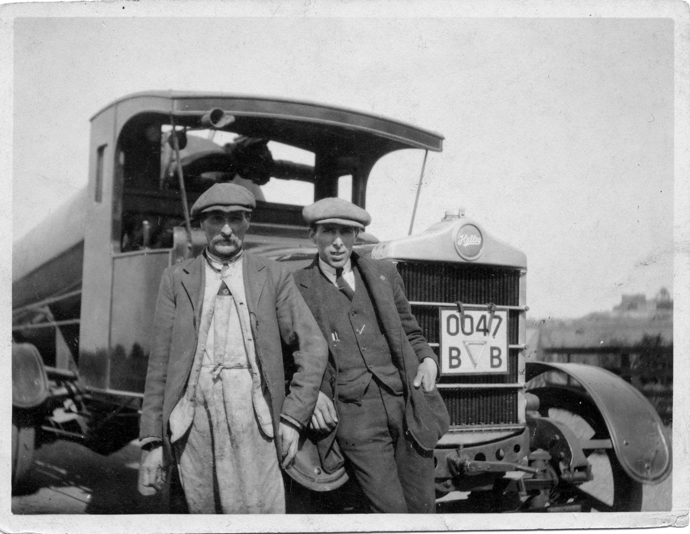 Two Halley workers standing beside a historic Halley vehicle